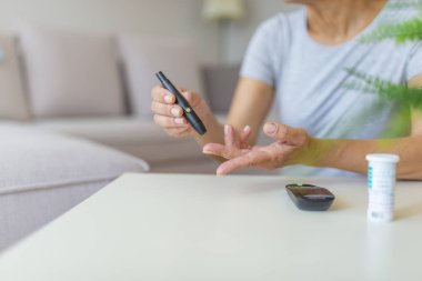 Kandaki glikoz seviyesini test alan kadının yakın çekim fotoğrafı. Kan şekeri ölçümü yapan lancet ve glucometer kullanan olgun kadın.