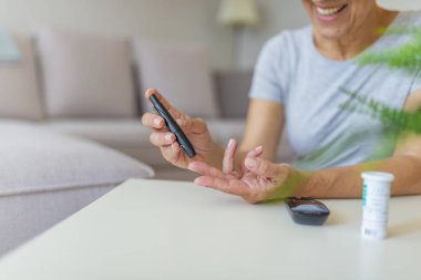Kandaki glikoz seviyesini test alan kadının yakın çekim fotoğrafı. Kan şekeri ölçümü yapan lancet ve glucometer kullanan olgun kadın.