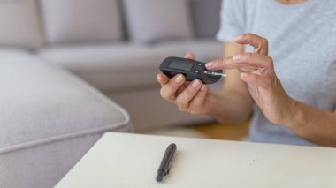 Parmağında lancelet kullanan kadın. Kan şekeri ölçümü yapan diyabet. Lancet ve glucometer kullanan kadın. Diyabet kan şekeri seviyesini kontrol ediyor. Evde lancelet ve glucometer kullanan kadın.