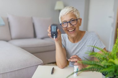 Olgun Kadın yüksek kan şekeri için test. Evde glucometer ve test şerit tarafından kan şekerini ölçmek için kadın tutma cihazı.