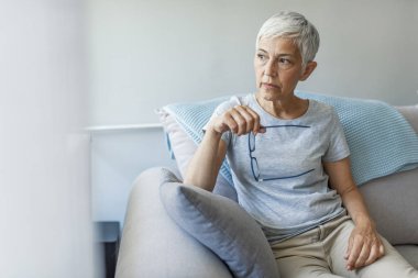 Evde pencereyakınında depresif yaşlı kadın. Yalnız yaşlı kadın. Dalgın kadın. Acı Çeken Olgun Kadın Pencereden Dışarı Bakıyor. 