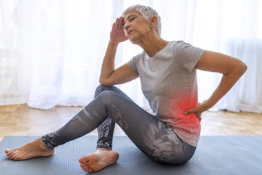 Matur Kadın bel ağrısı muzdarip. Sırt ağrısıyla dinlenmiş olgun bir kadın. Kadın bel ağrısı. Fitness sırt ağrısı neden muzdarip Kıdemli kadın yaralanma.