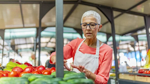 Çiftçi pazarında organik taze tarım ürünleri satan manav. Çiftçiler Taze Gıda Pazarı'nda Kadın Tezgah Sahibi. Pazar Da Çiftlikten Taze Yerel Sebze Satan Kıdemli Kadın