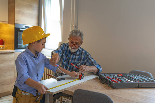 Grandfather and grandson in workshop. Grandfather and grandson crafting wooden materials. My grandson is little carpenter. Grandfather Teaching Boy Carpentry 