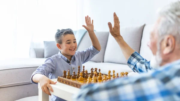 Šťastný Chlapec Hraje Šachy Starým Starším Mužem Doma Boční Pohled — Stock fotografie