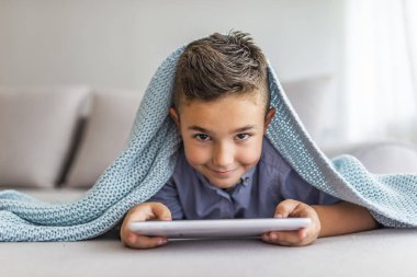 Tablet Pc modern çocuk ve eğitim teknolojisi üzerinde karikatür izlerken evde küçük bir çocuğun portresi. Tablet bilgisayarda oyun oynayan memnun sevimli küçük bir çocuk Portresi