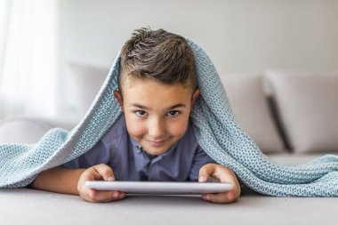 Küçük sevimli çocuk bir tablet üzerinde oyun oynarken ve çizgi film izlerken. Dokunmatik yüzeyli küçük çocuk, erken eğitim ve öğrenme. Dijital tablet Pc'de oynayan çocuk