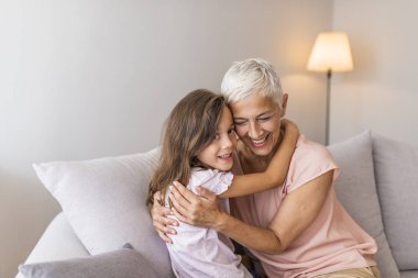 Mutlu büyükanne ve torunu kucaklayan, alınlarına dokunan, hassas anların tadını çıkaran, evde birlikte oturan, büyükanne ve torun birlikte vakit geçiren. Büyükannesi ile lovely küçük kız