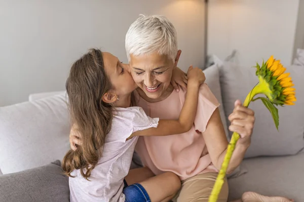 Little Preschool Granddaughter Kissing Happy Older Grandma Cheek Giving Sunflower — Stock Photo, Image