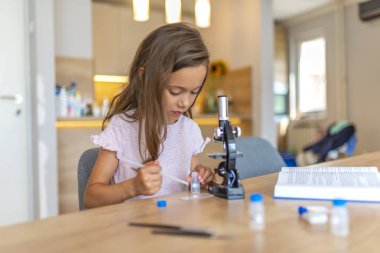 Meraklı Küçük Bilim Adamı Portresi. Güzel ilkokul öğrencisi bilim projesi için bir mikroskop kullanır. Küçük kız mikroskop kullanırken konsantre olur. Okul konseptine geri dön.