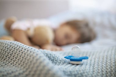 Bebek çocuk oyuncak ayı ve emzik ile uyuyor. Uyku zamanı kavramı. Emziğe odaklan. Bebeğin uykuya ihtiyacı var! Sabah uykusu. Sevimli küçük çocuk uyuyor. Yatakta uyuyan bebek, elinde oyuncak ayı.