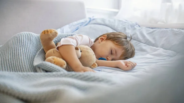 眠い頭青い枕の上で安らかに眠っている少年 赤ちゃんは彼の睡眠を必要とします テディベアとおしゃぶりと寝ている男の子 柔らかい毛布で覆われた赤ちゃんの睡眠 — ストック写真
