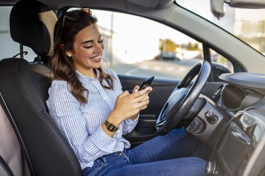 Kadın sürücü arabada akıllı telefon kullanıyor. Kadın sürücü arabada akıllı telefon kullanıyor. Eğlence, yolculuk, teknoloji, seyahat ve insanların konsepti - akıllı telefonlu mutlu kadın araba kullanıyor
