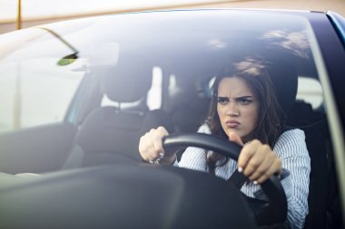 Stresli kadın sürücü arabasında oturuyor. Kızgın kadın sürücü araba kullanıyor. Kızgın genç kadın bir trafik sıkışıklığında sıkışmış. Arabada rahatsız bir kadın. Trafiğe takılan kız.