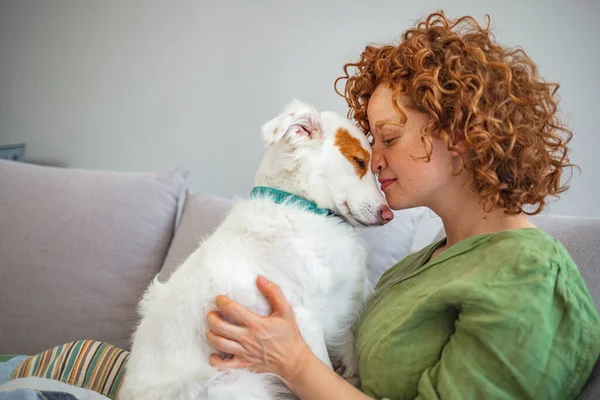 Lifestyle woman with her dog relaxing in living room. Happiness is a warm puppy. Shot of an attractive young woman relaxing at home on the weekend. Portrait of woman with dog