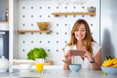 Yemek blogcusu yemek fotoğrafı çekiyor. Genç bir yemek blogcusunun portresi, blog / vlog 'u için içeriği fotoğraflıyor. Kahvaltıyı akıllı telefonuyla çeken kadın.