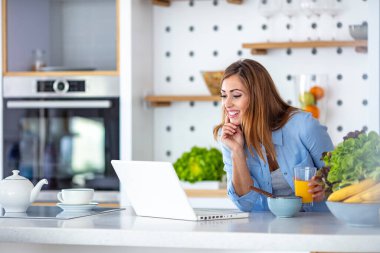 Acele kahvaltı, yemek, içmek ve okumak aynı zamanda güzel genç bir kadının sabah kahvaltı masasında otururken dizüstü bilgisayarda çalışması.. 