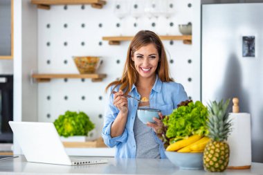 Acele kahvaltı, yemek, içmek ve okumak aynı zamanda güzel genç bir kadının sabah kahvaltı masasında otururken dizüstü bilgisayarda çalışması.. 