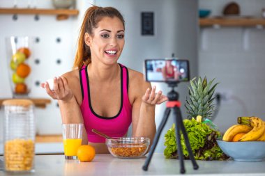 Bir fitness kadını tavuk yumurtalarını gösteriyor. Onları elinde tutuyor ve arka planda da bir mutfak var. Gülümseyen Kadın Yumurta Tutuyor. Fitness kadını sağlıklı bir kahvaltı hazırla..
