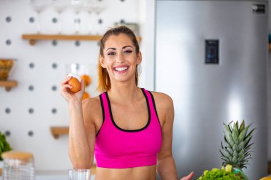 Güzel, genç bir kadın evde elleriyle yumurta gösteriyor. Fitness kadını kahvaltı hazırlar. Sebzeli ev yapımı yulaf ezmesi. Taze Yumurtalar 