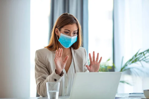 Safety during COVID-19 pandemic. Businesswoman wearing mask in the office during COVID-19 pandemic. Businesswoman in medical face protection mask. Business woman with mask working in the office on laptop. Concept, contagious disease, coronavirus.