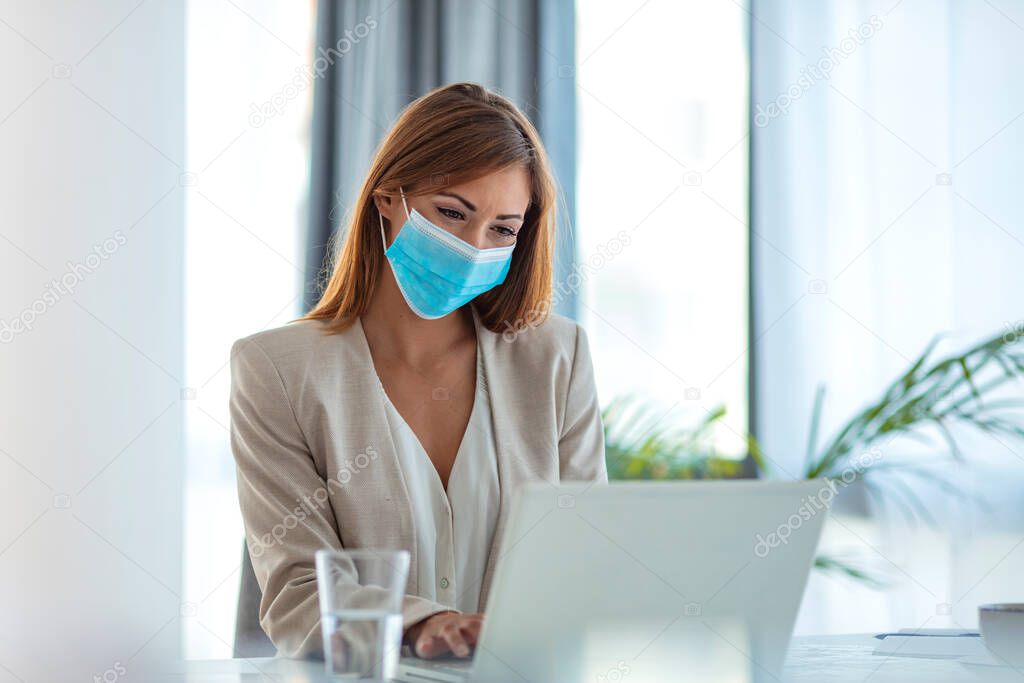 Safety during COVID-19 pandemic. Businesswoman wearing mask in the office during COVID-19 pandemic. Businesswoman in medical face protection mask. Business woman with mask working in the office on laptop. Concept, contagious disease, coronavirus.