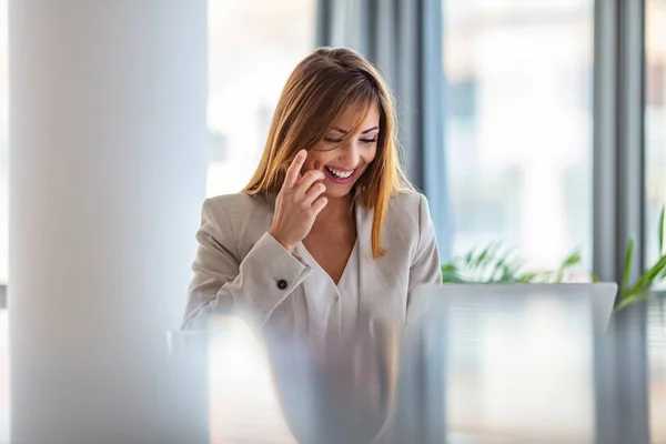 Horizontal shot of pleasant looking successful professional female lawyer learns clients case, works on modern laptop computer, dressed in formal apparel. Shot of a cheerful young businesswoman