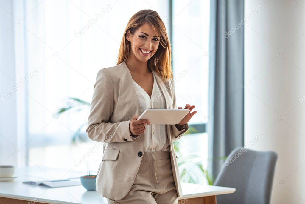 Portrait of young white woman in a busy modern workplace. Portrait of successful businesswoman standing at the office. MProfessional woman looking at camera and smiling.