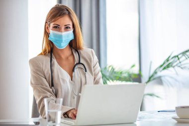 Yüzünde ameliyat maskesi olan genç bir tıp uzmanı. Çevrimiçi ev ziyareti sırasında sağlık ziyaretçisi portresi. Tıp, sağlık, insan konsepti, kendine güvenen profesyonel uzmanların portresi..