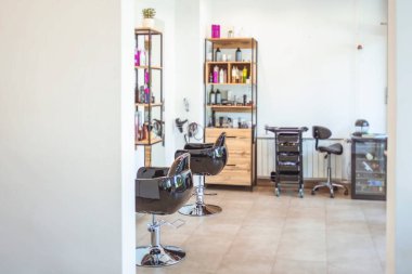 Berber dükkanında boş siyah sandalyeler ve aynalar. Aydınlatılmış kuaför salonu. Modern kuaför salonu. Modern kuaför salonunun içi boş.