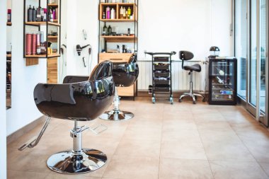 Berber dükkanında boş siyah sandalyeler ve aynalar. Aydınlatılmış kuaför salonu. Modern kuaför salonu. Modern kuaför salonunun içi boş.