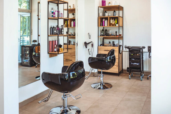 Workshop of hairdressers. Beauty salon with chairs, hair dryers, combs and mirrors. Interior of empty modern hair and beauty salon. Barbershop interior. 