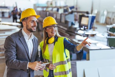 Fabrika ortamında proje planlama, takım çalışması, yenilik ve üretkenlik konularında iki endüstriyel profesyonel işbirliği yapmaktadır. Koruyucu miğferler takarlar, imalatta işyeri güvenliği ve verimliliğe odaklanırlar..