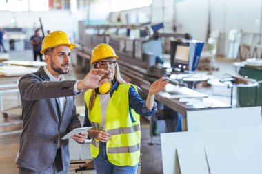 Bir fabrikada profesyonel takım çalışması, bir endüstriyel çalışma alanında makinelerle işbirliği ve tartışma sergiliyor.