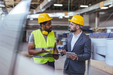 Ekip çalışması ve üretkenliği vurgulayarak, büyük bir endüstriyel tesiste danışmanlık ve strateji alanında çalışan iki profesyonel.