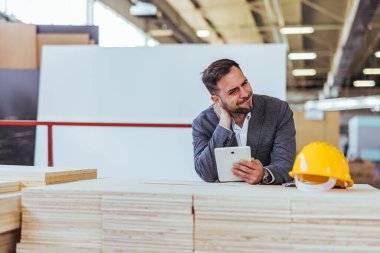 Modern bir inşaat ortamında dijital tabletle site planlarını mimar analiz eder. Mimarlık, mühendislik ve inşaat sektörlerinde profesyonellik, hazırlık ve güvenliğin vurgulanması.