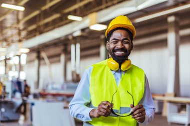 İnşaat alanında güvenlik kaskı ve gözlüklü Afro-Amerikan mimar.