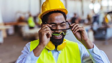 İnşaat alanında güvenlik kaskı ve gözlüklü Afro-Amerikan mimar.