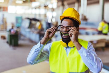 İnşaat alanında güvenlik kaskı ve gözlüklü Afro-Amerikan mimar.