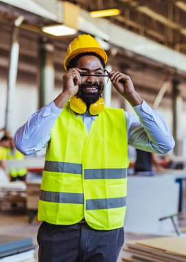 İnşaat alanında güvenlik kaskı ve gözlüklü Afro-Amerikan mimar.