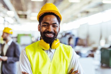 Endüstriyel fabrikada miğferi olan Afrikalı Amerikan işçisinin portresi.