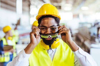 Endüstriyel fabrikada miğferi olan Afrikalı Amerikan işçisinin portresi.