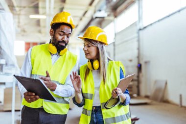 İnşaat alanında panolarla çalışan iki mimar.