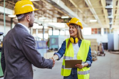 Koruyucu ekipman kullanan iki mühendis bir imalat tesisinde ekip çalışmasını ve güvenliği sembolize ediyor..