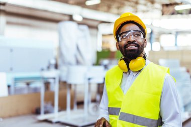 Depoda sarı kasklı ve güvenlik gözlüklü Afro-Amerikan erkek mühendis