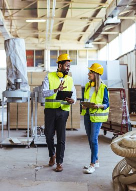 Profesyonel endüstriyel işçiler koruyucu giysiler giyer ve fabrikada yürürken görevleri tartışırlar. Başarılı sanayi operasyonları için işyerinde takım çalışması, güvenlik ve işbirliğini teşvik eder.