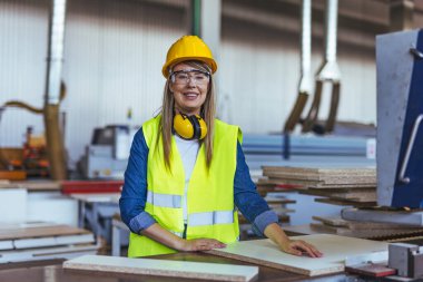 Fabrikada kasketli, koruyucu gözlüklü ve kulak koruyucu takan bir kadın işçi.. 