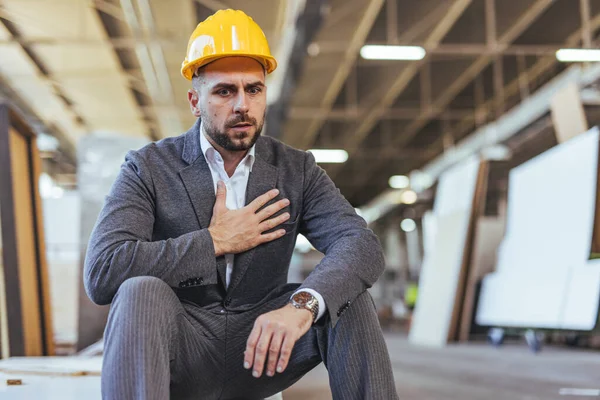 Endüstriyel bir ortamda otururken güvenlik ekipmanı takan düşünceli bir inşaat işçisi. Sahne, işle ilgili stres, karar verme ve inşaat ortamındaki zorlukları aktarıyor.