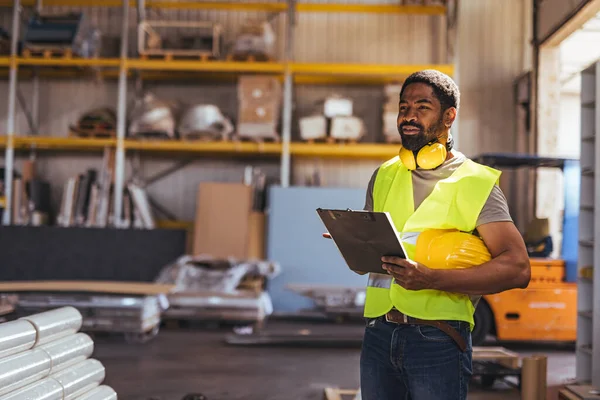 Güvenilir bir işçi elinde bir pano ile depoda envanter incelemesi yapıyor..