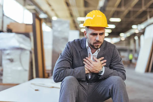 Başlık takan ilgili bir işçi bir fabrikada stresli bir şekilde oturur. Görüntü, duyguları ve endüstriyel bağlamı yakalıyor.